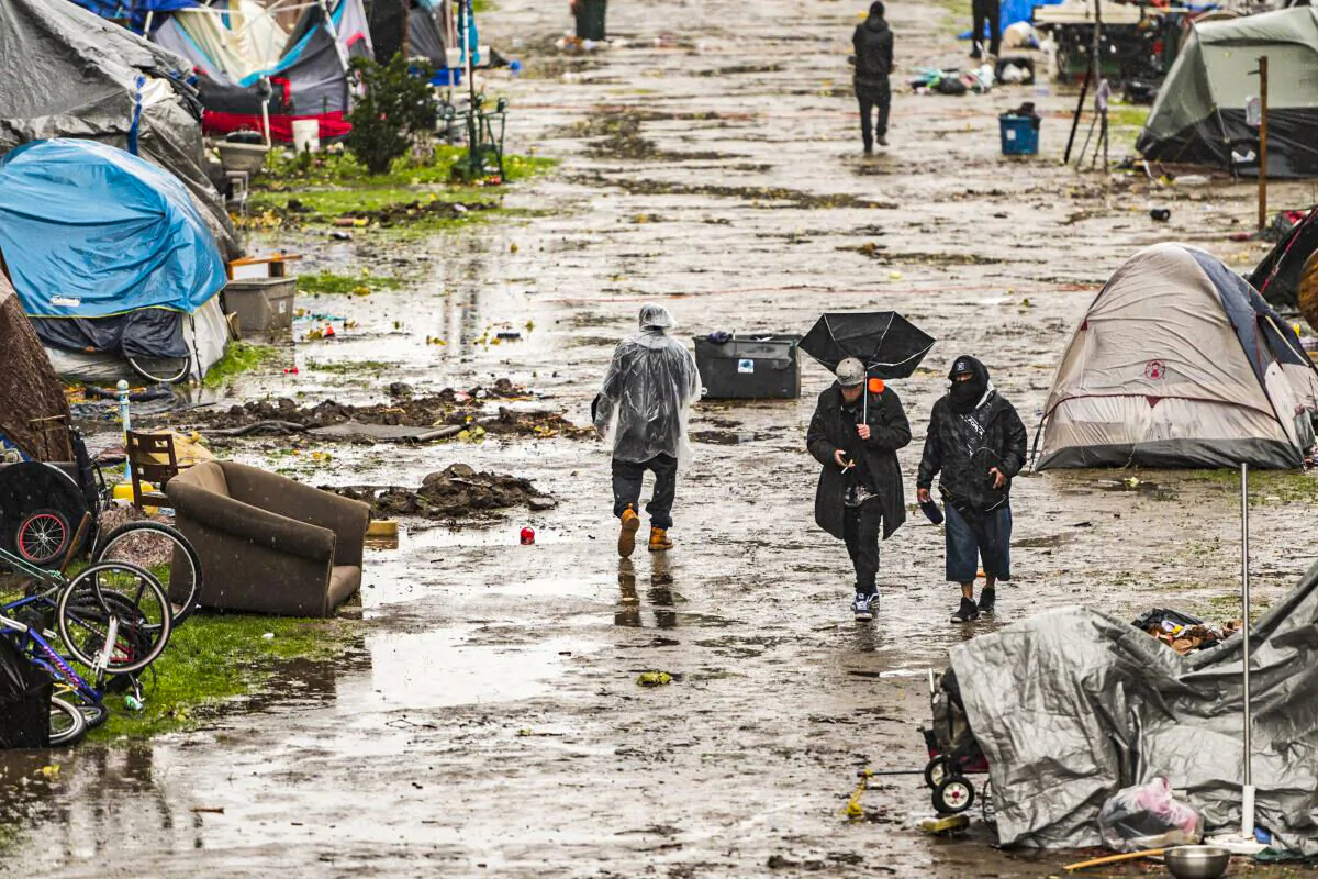 People walk through a partially flooded homeless encampment at Riverwalk Park in Santa Cruz, Calif., on Dec. 13, 2021. (Nic Coury/AP Photo)