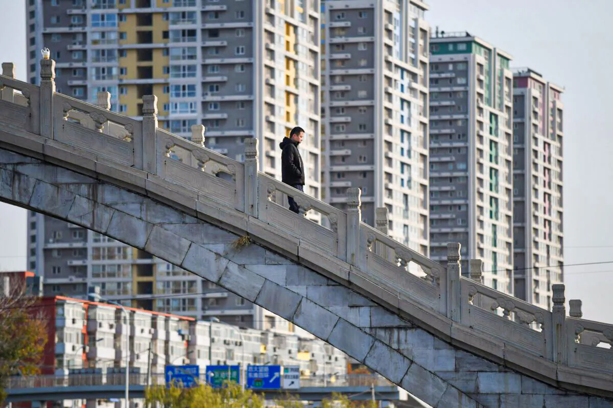 A man crosses a bridge near an apartment complex in Beijing on Dec. 1, 2020. (Greg Baker/AFP via Getty Images)