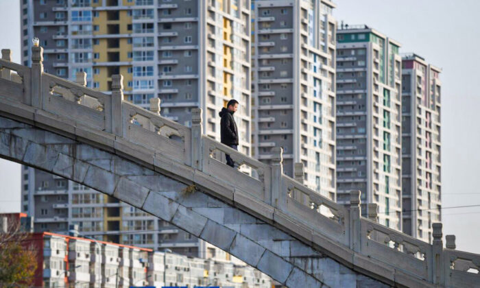 A man crosses a bridge near an apartment complex in Beijing on Dec. 1, 2020. (Greg Baker/AFP via Getty Images)