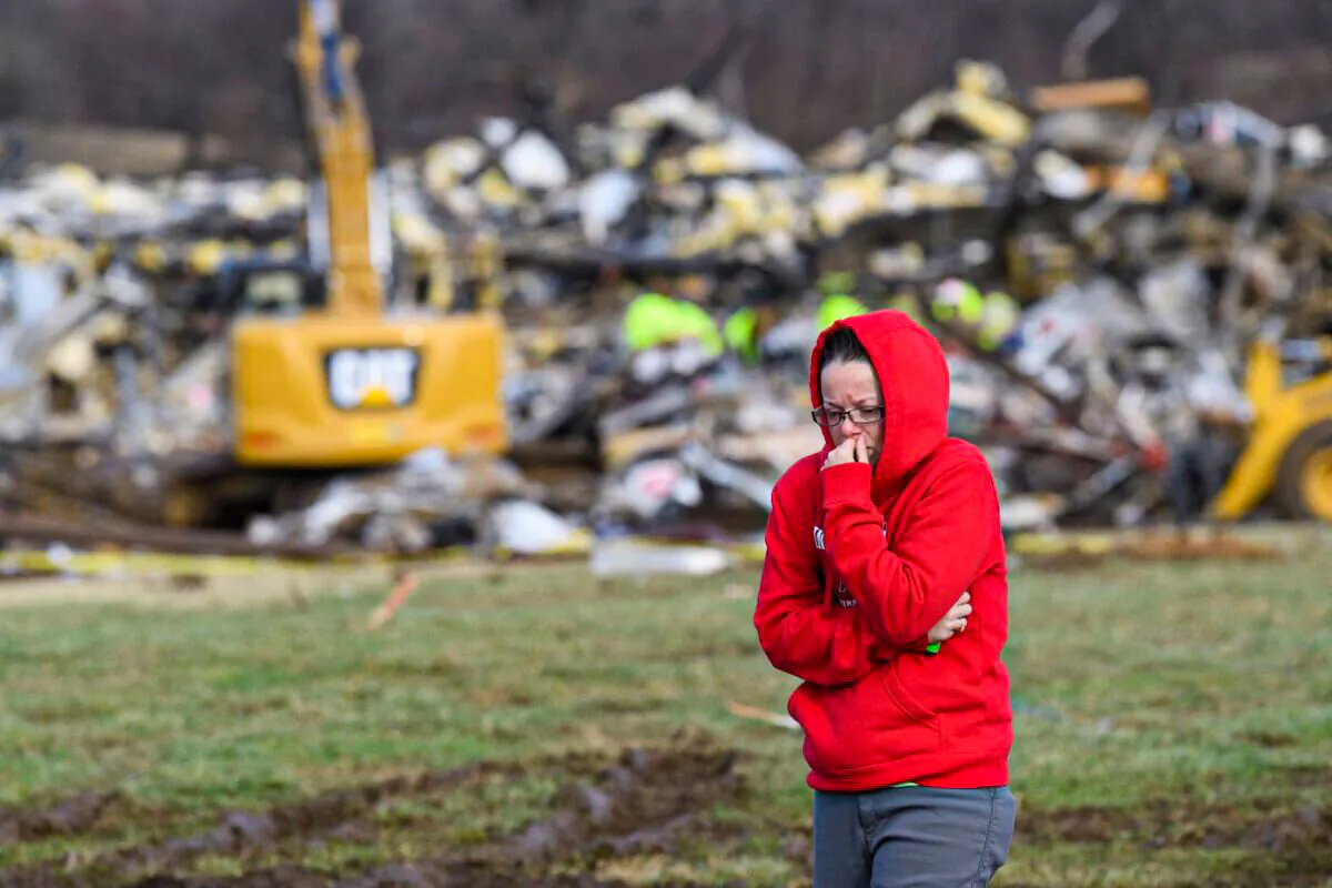 A woman walks away from what is left of the Mayfield Consumer Products Candle Factory as emergency workers combed the rubble after it was destroyed by a tornado in Mayfield, Kentucky, on Dec. 11, 2021. (John Amis/AFP via Getty Images)