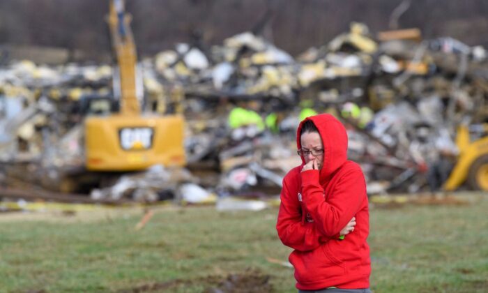 A woman walks away from what is left of the Mayfield Consumer Products candle factory as emergency workers combed the rubble after it was destroyed by a tornado in Mayfield, Ky., on Dec. 11, 2021. (John Amis/AFP via Getty Images)