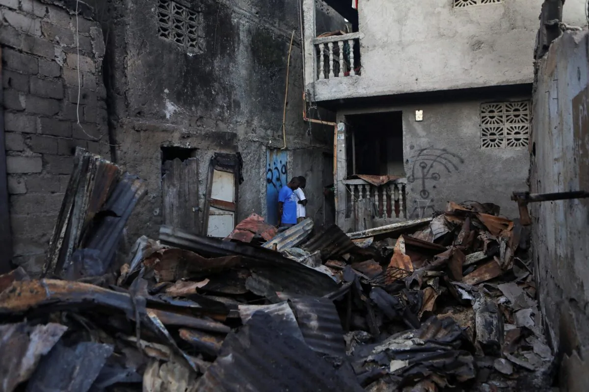 People stand next to the remains of damaged buildings after a fuel truck exploded, killing dozens of people in Cap Haitien, Haiti, on Dec. 15, 2021. (Ralph Tedy Erol/Reuters)
