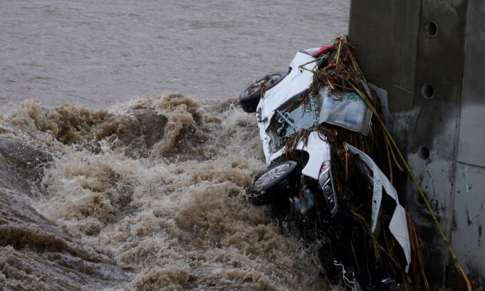 A submerged vehicle is wedged against a bridge pillar in the surging Los Angeles River making it difficult for firefighters to access it on Dec. 14, 2021. (Damian Dovarganes/AP Photo)
