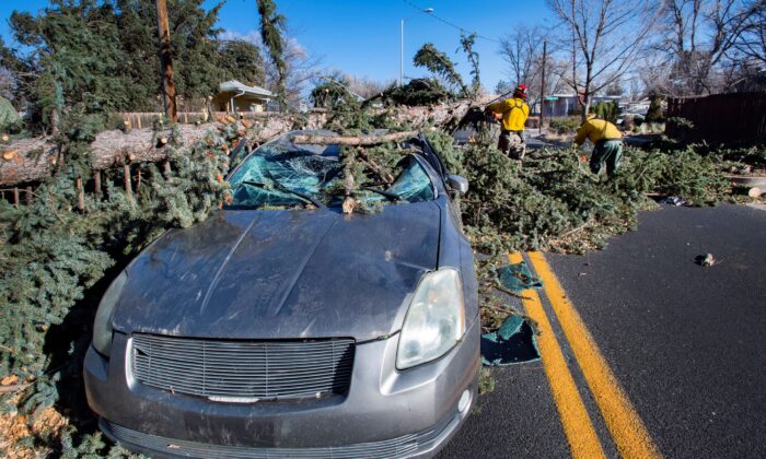 Members of the Colorado Springs Utilities Catamount crew remove a fallen tree that crushed a car driving westbound on Unitah Street in Colorado Springs, Colo., as wind gusts reached more than 100 mph in the Pikes Peak Region on Dec. 15, 2021. (Christian Murdock/The Gazette via AP)