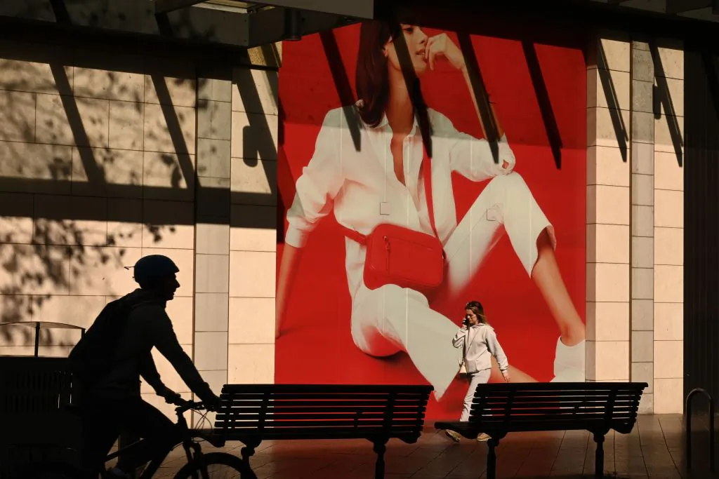 People walk past an advertising billboard along a street in Sydney, Australia on July 21, 2020. (Peter Parks/AFP via Getty Images)
