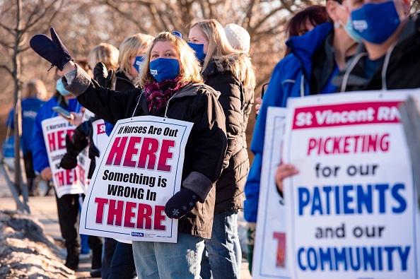 Registered nurses and supporters stand in a picket line and wave to cars as they drive by outside St. Vincent Hospital in Worcester, Mass., on February 24, 2021. (Photo by JOSEPH PREZIOSO/AFP via Getty Images)