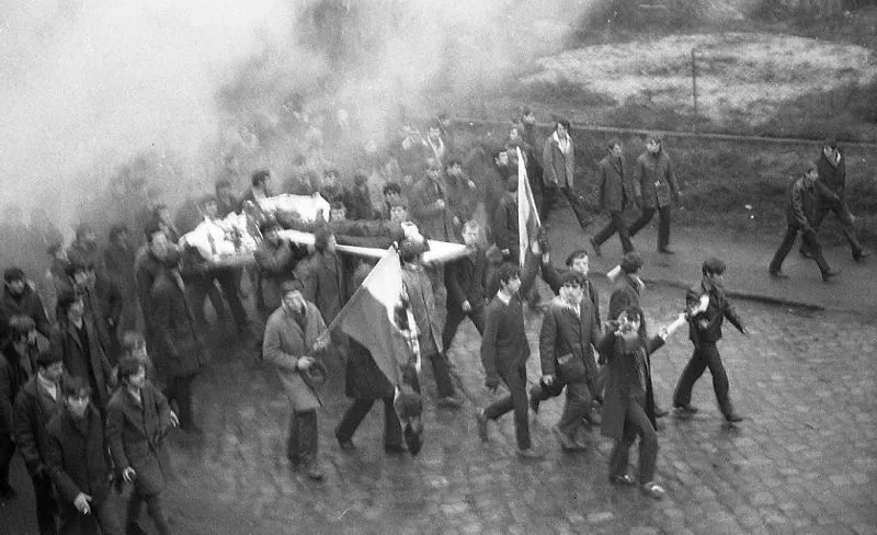 People march along Czerwonych Kosynierów Street carrying the body of Zbigniew Godlewski on a door. Zbigniew Godlewski died in the vicinity of the Gdynia Shipyard station of the commuter rail, shot with a firearm in Gdynia, Poland, on Dec. 17, 1970. (Institute of National Remembrance (IPN)/ Portal https://polskiemiesiace.ipn.gov.p)