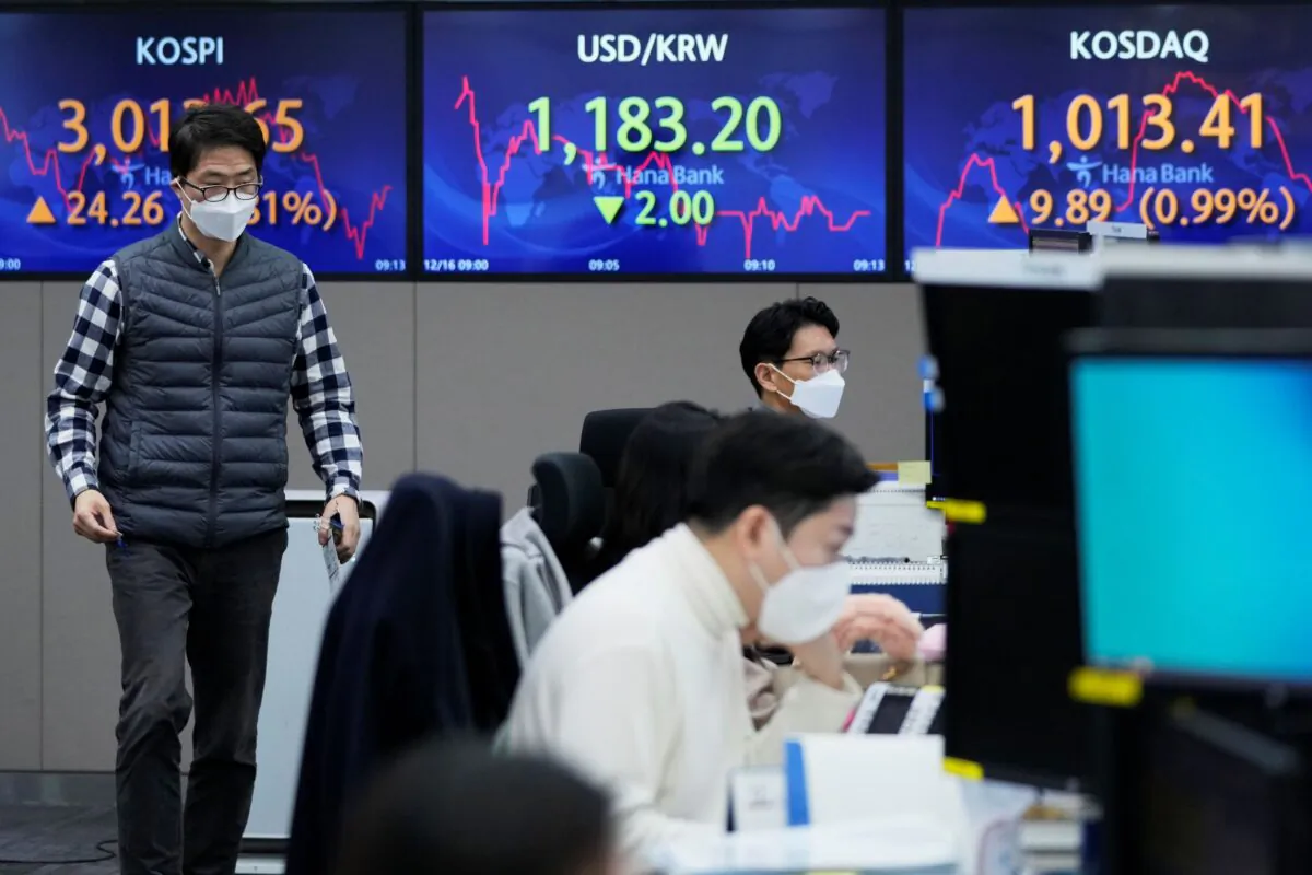 A currency trader passes by screens showing the Korea Composite Stock Price Index (KOSPI) (L) and the foreign exchange rate between U.S. dollar and South Korean won (C) at the foreign exchange dealing room of the KEB Hana Bank headquarters in Seoul, South Korea, on Dec. 16, 2021. (Ahn Young-joon/AP Photo)