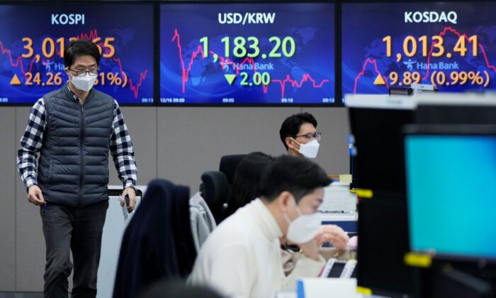 A currency trader passes by screens showing the Korea Composite Stock Price Index (KOSPI) (L) and the foreign exchange rate between U.S. dollar and South Korean won (C) at the foreign exchange dealing room of the KEB Hana Bank headquarters in Seoul, South Korea, on Dec. 16, 2021. (Ahn Young-joon/AP Photo)