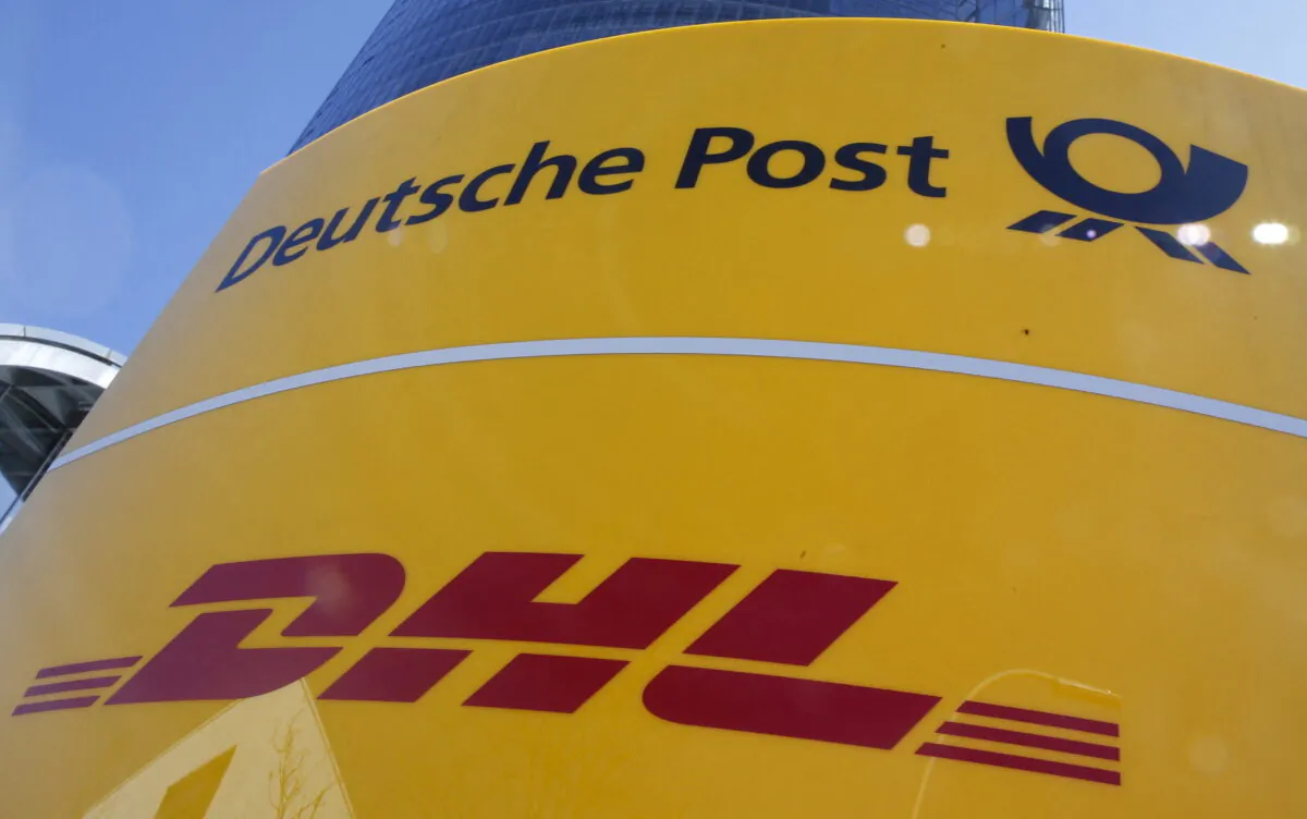 A Deutche Post and DHL sign stands in front of the Bonn Post Tower, the headquarters of German postal and logistics group Deutsche Post DHL in Bonn, Germany, on March 11, 2015.  (Wolfgang Rattay/Reuters)