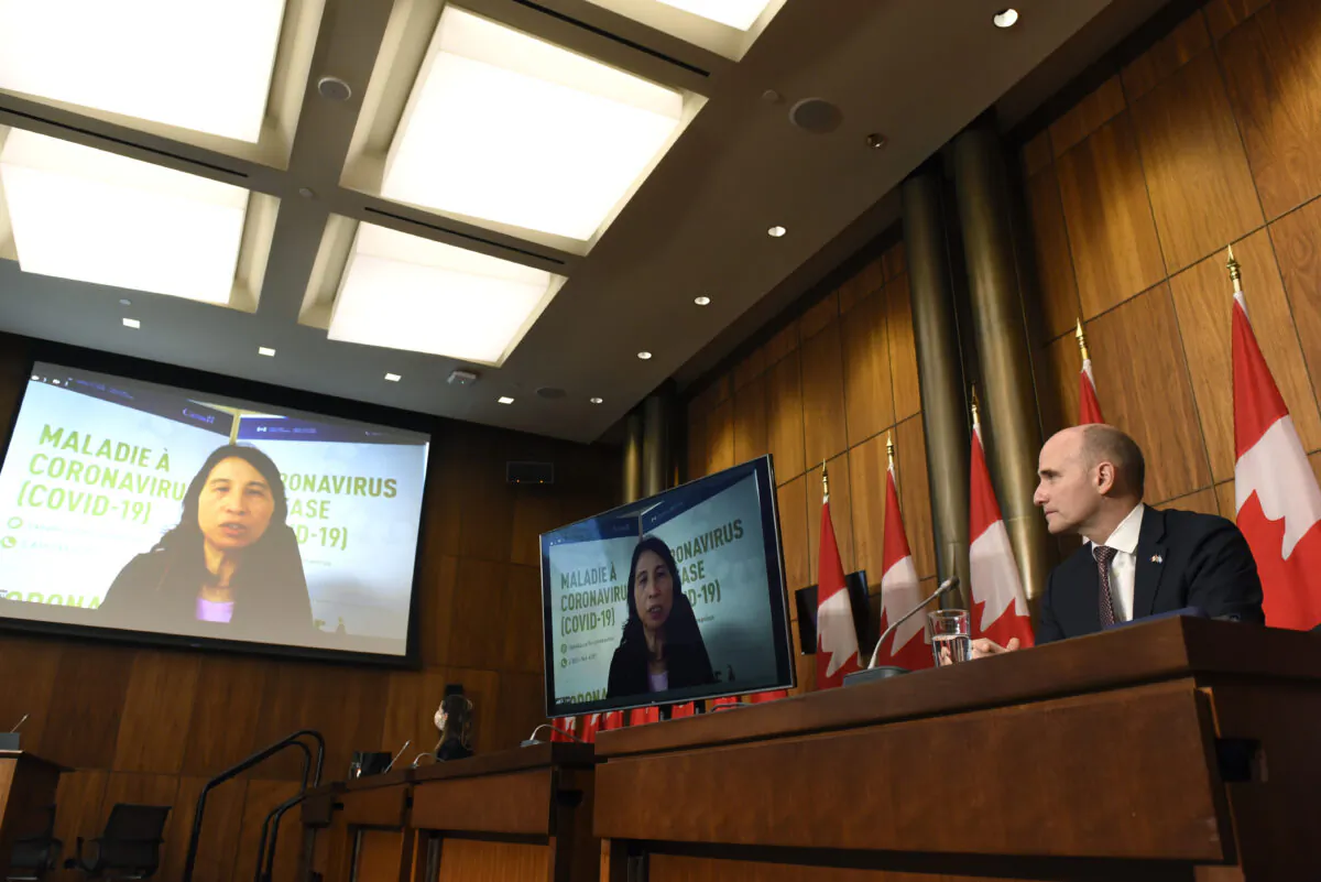 Minister of Health Jean-Yves Duclos listens as Chief Public Health Officer of Canada Dr. Theresa Tam appears via videoconference during a news conference on the COVID-19 pandemic and the Omicron variant, in Ottawa on Dec. 17, 2021. (The Canadian Press/Justin Tang)