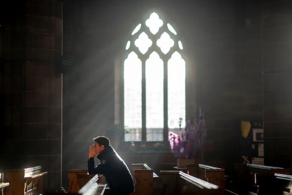 A man prays in a church as shoppers make their last minute purchases on Christmas Eve in Birmingham, England, on Dec. 24, 2018. (Christopher Furlong/Getty Images)