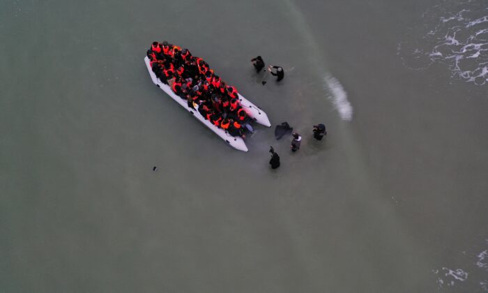 A drone photo showing a group of illegal immigrants react as they succeeded to get on an inflatable dinghy, to leave the coast of northern France and to cross the English Channel, in Wimereux near Calais, France, on Dec. 16, 2021. (Pascal Rossignol/Reuters)