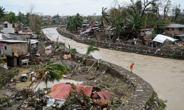 A man stands beside damaged homes along a swollen river due to Typhoon Rai in Talisay, Cebu Province, central Philippines, on Dec. 17, 2021. (Jay Labra/AP Photo)