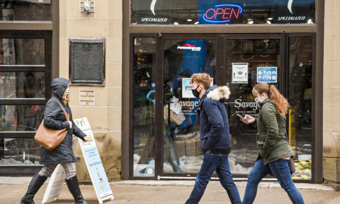 Pedestrians walk past a bicycle business in downtown Fredericton, New Brunswick, on Feb. 4, 2021. (Stephen MacGillivray/The Canadian Press)