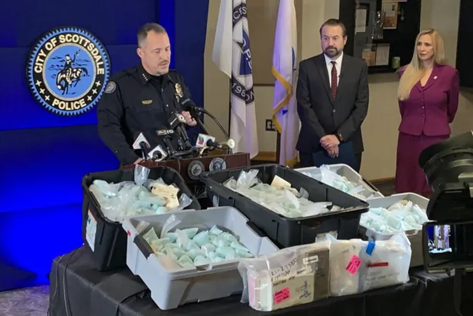 Scottsdale Police Chief Jeff Walther in front of a display of illicit fentanyl-laced pills and other narcotics; Arizona Attorney General Mark Brnovich, and Cheri Oz, special agent in charge of the DEA’s Phoenix field division at a press conference in Scottsdale, Ariz., on Dec. 16, 2021. (Scottsdale PD)