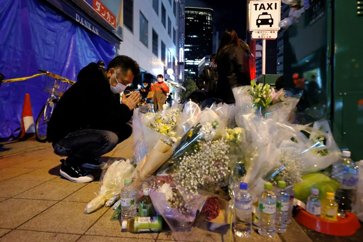 A mourner prays in front of offerings near a building where a fire broke out, in Osaka, western Japan, on Dec. 18, 2021. (Kyodo News via AP)