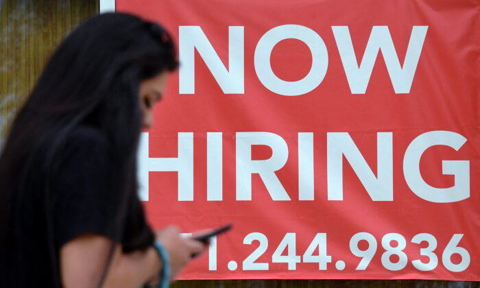 A woman walks by a "Now Hiring" sign outside a store in Arlington, Va., on Aug. 16, 2021. (Olivier Douliery/AFP via Getty Images)