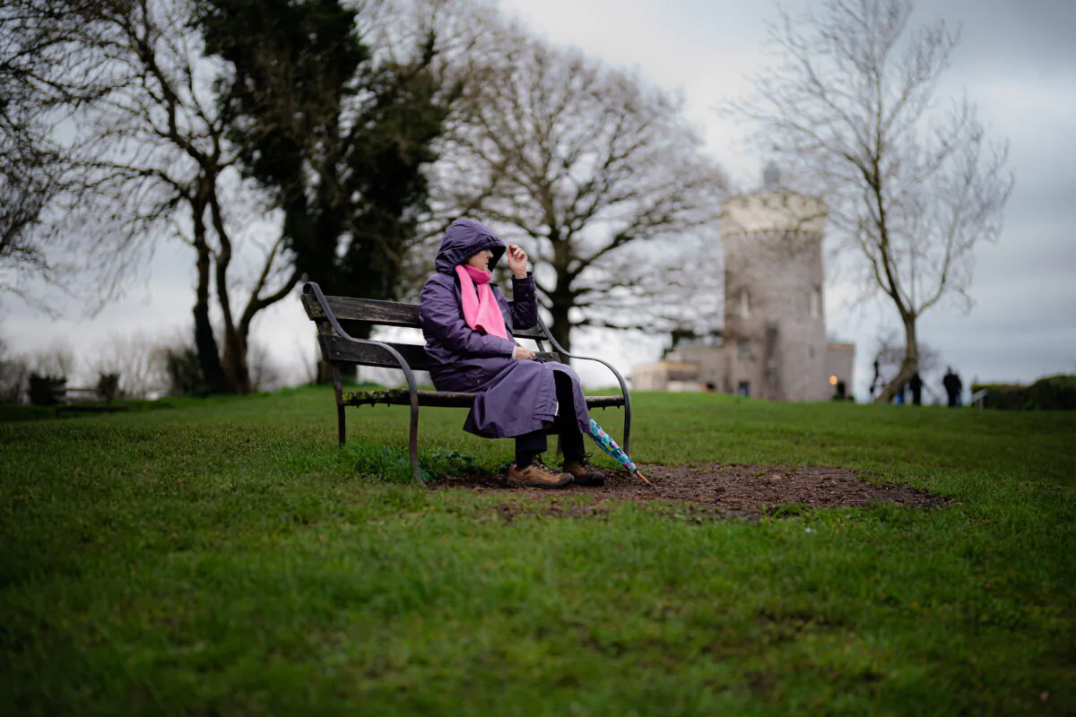 A woman sits on a bench in Clifton, Bristol, England on Dec. 30, 2021. (Ben Birchall/PA)