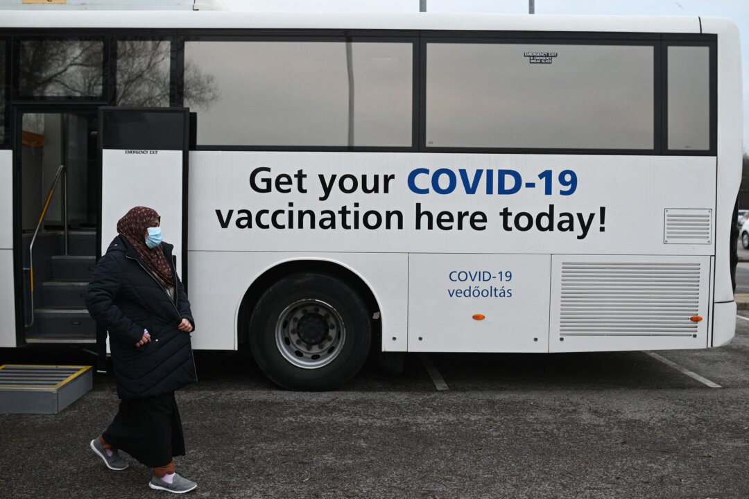 Members of the public receive their COVID-19 vaccine or booster at an NHS bus outside an Asda supermarket in the town of Farnworth, near Manchester in northwest England on Dec. 20, 2021. (Oli Scarff/AFP via Getty Images)