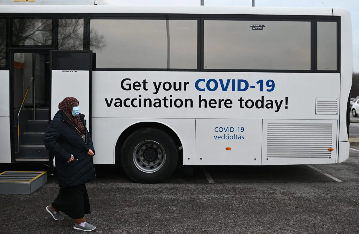 Members of the public receive their COVID-19 vaccine or booster at a NHS (National Health Service) bus outside an Asda Supermarket in the town of Farnworth, near Manchester in north-west England on Dec. 20, 2021. (Oli Scarff/AFP via Getty Images)