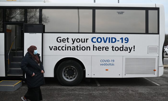 Members of the public receive their COVID-19 vaccine or booster at a NHS (National Health Service) bus outside an Asda Supermarket in the town of Farnworth, near Manchester in north-west England on Dec. 20, 2021. (Oli Scarff/AFP via Getty Images)