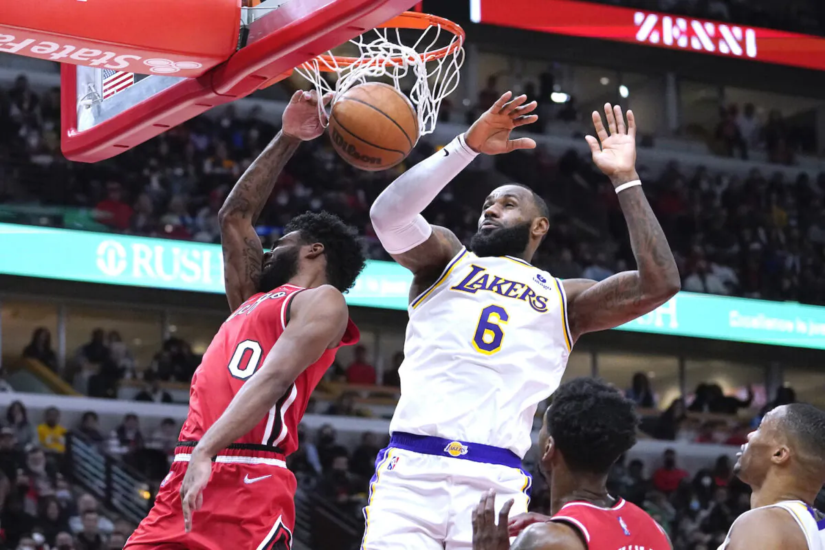 Chicago Bulls guard Coby White, left, dunks past Los Angeles Lakers forward LeBron James (6) during the second half of an NBA basketball game in Chicago on Dec. 19, 2021. (AP Photo/Nam Y. Huh)