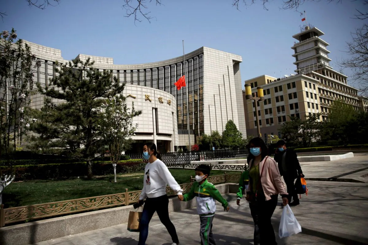 People wearing face masks walk past the headquarters of the Chinese central bank, on April 4, 2020. (Tingshu Wang/Reuters)