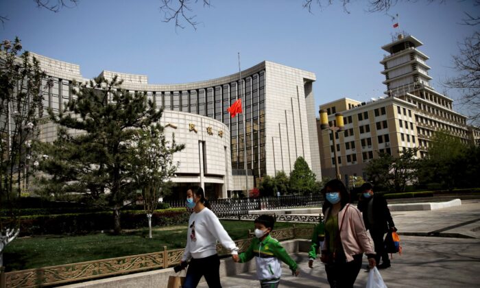 People wearing face masks walk past the headquarters of the Chinese central bank, on April 4, 2020. (Tingshu Wang/Reuters)