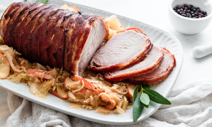This take on pork and sauerkraut calls for the pork loin to be dry-brined, wrapped in bacon, and roasted until tender, then paired with bright and tangy cider-braised sauerkraut and apples. (Jennifer McGruther)