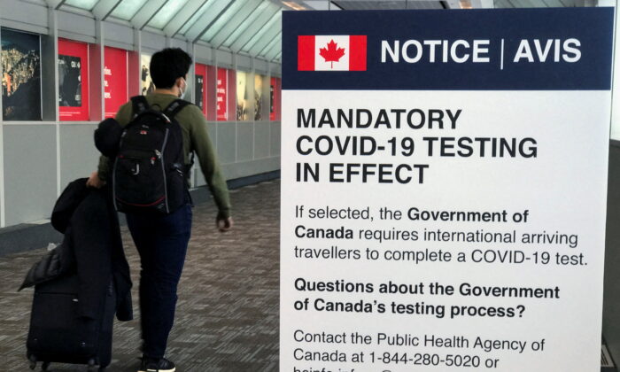 A traveler walks past a "Mandatory COVID-19 Testing" sign at Pearson International Airport during the coronavirus disease (COVID-19) pandemic of Toronto, Ontario, Canada, on Dec. 18, 2021.  (Carlo Allegri/Reuters)
