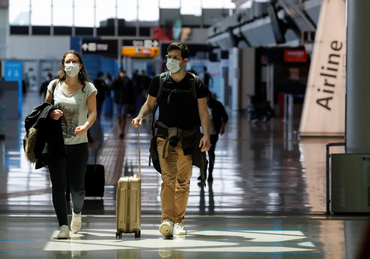 Travelers walk with their luggage at Fiumicino Airport near Rome, Italy, on May 17, 2021. (Remo Casilli/Reuters)