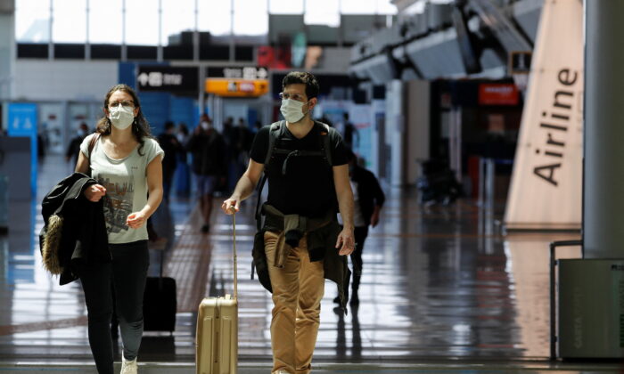 Travelers walk with their luggage at Fiumicino Airport near Rome, Italy, on May 17, 2021. (Remo Casilli/Reuters)