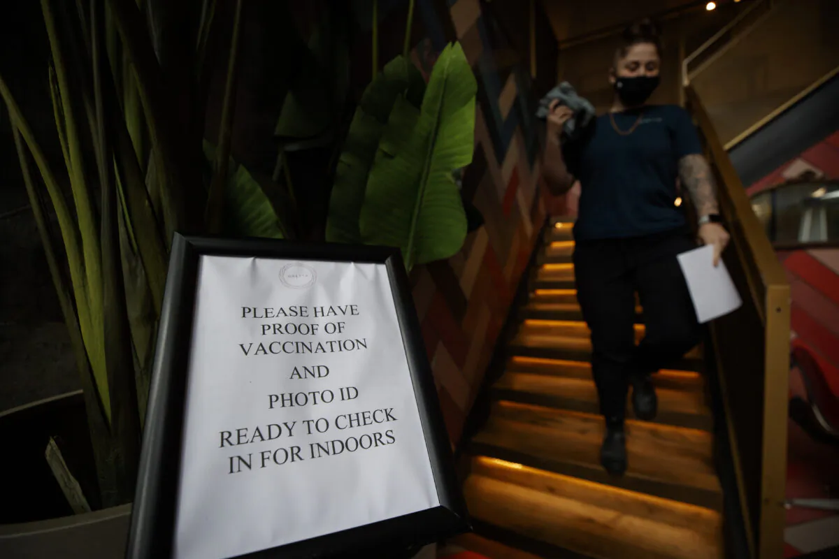 A staff member walks by a sign telling customers to show their proof of vaccine at a cafe in Toronto on Sept. 22, 2021. (THE CANADIAN PRESS/Cole Burston)