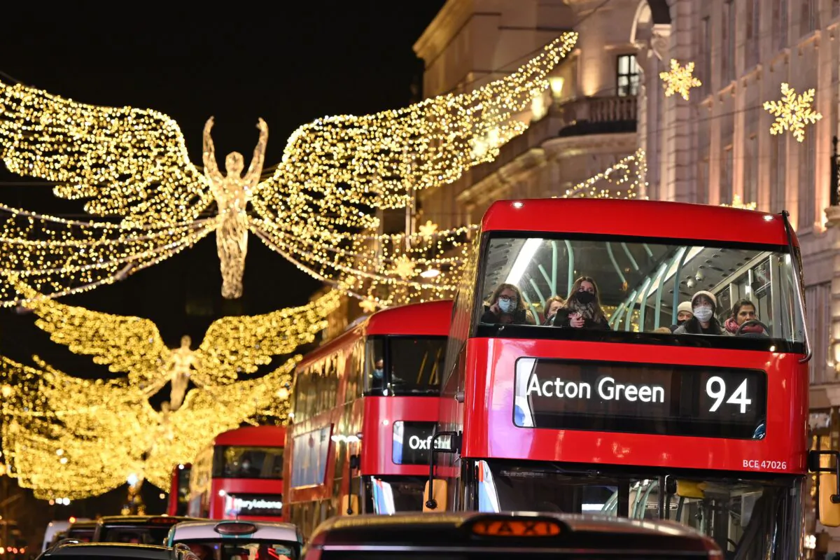 Passengers, some wearing face coverings to combat the spread of the coronavirus, sit on the top deck of a red double-decker London bus travelling beneath the Christmas lights in central London on Dec. 21, 2021. (Justin Tallis/AFP via Getty Images)