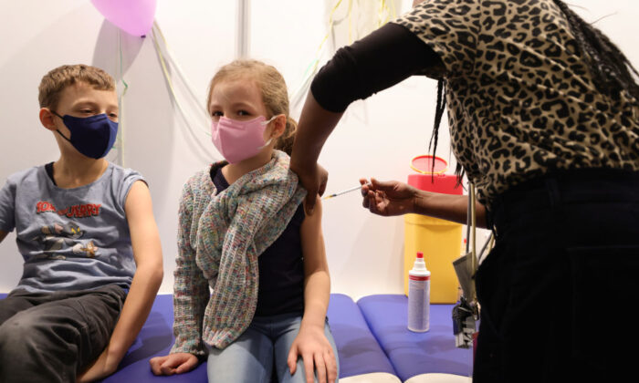 Children receive a dose of COVID-19 Pfizer-BioNTech Comirnaty vaccine for children at the children's section of the Lanxess Arena vaccination center in Cologne, Germany, on Dec. 18, 2021. (Andreas Rentz/Getty Images)