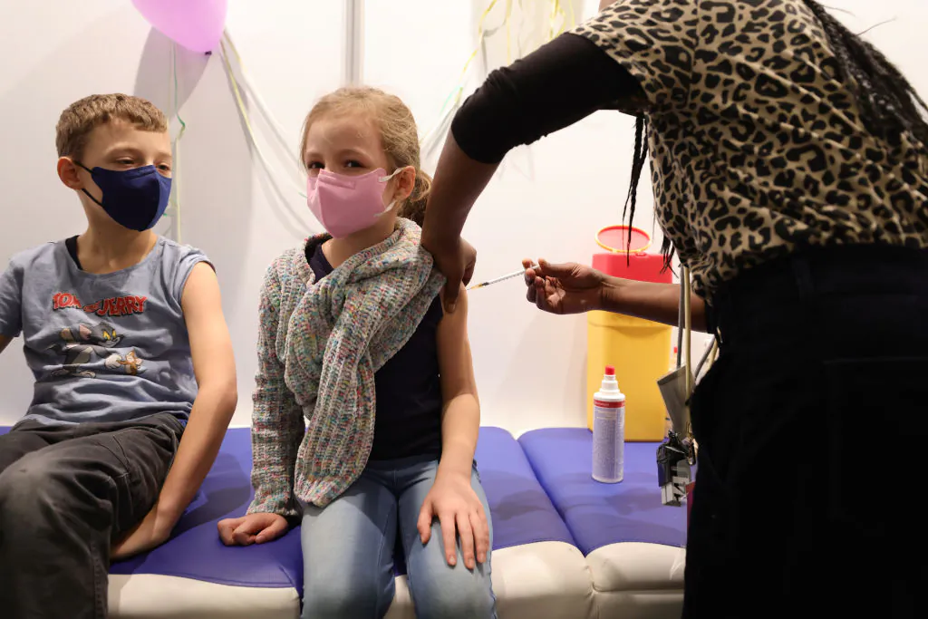 Children receive a dose of COVID-19 Pfizer-BioNTech Comirnaty vaccine for children at the children's section of the Lanxess Arena vaccination center in Cologne, Germany, on Dec. 18, 2021. (Andreas Rentz/Getty Images)