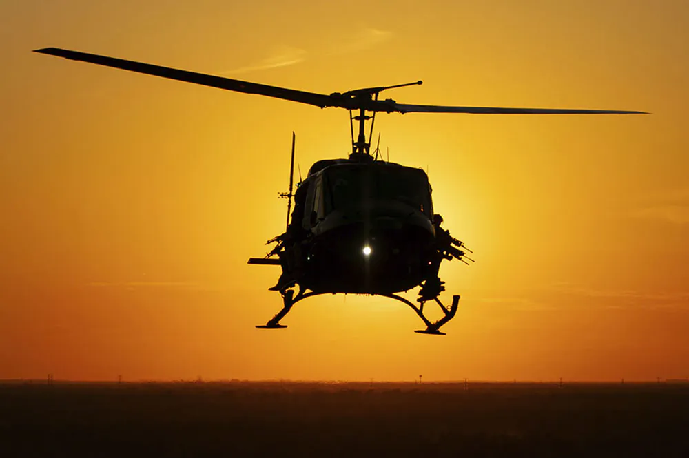 Gunners watch from the doors of a Helibacon helicopter at sunset. (HeliBacon)