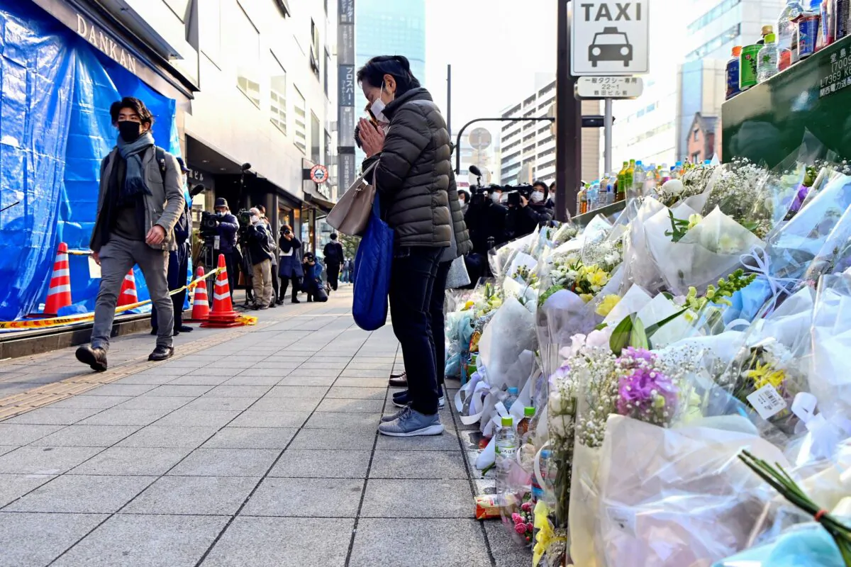 A woman offers prayers in front of a building damaged by last Friday's deadly fire in Osaka, western Japan, on Dec. 21, 2021. (Kyodo News via AP)