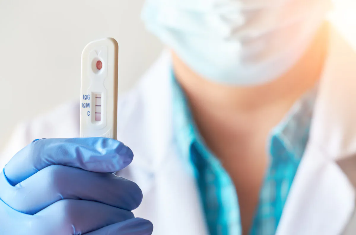 Doctor or medtech shows rapid laboratory COVID-19 test to detect IgM and IgG antibodies to Novel Coronavirus, SARS-CoV-2 with positive result. Immunity against Covid-19, respiratory viral pneumonia. (anyaivanova/Shutterstock)