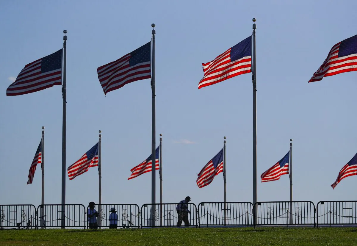 People walk beneath U.S. flags surrounding the Washington monument on the National Mall near the White House in Washington on Nov. 10, 2020. (Tom Brenner/Reuters)
