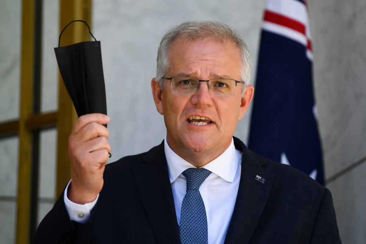 Australian Prime Minister Scott Morrison holds up a face mask as he speaks during a press conference at Parliament House in Canberra, Australia, on Dec. 22, 2021. (AAP Image/Lukas Coch)