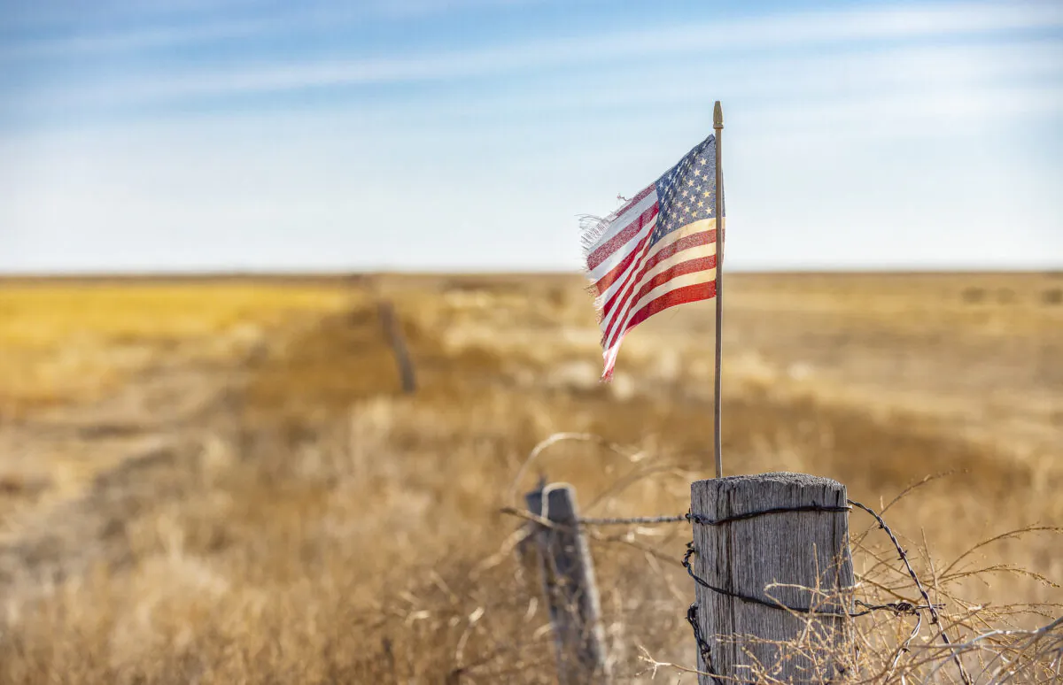 An American flag waves in the window at the edge of a farm outside of Walsh, Colorado, on Dec. 6, 2021. (John Fredricks/The Epoch Times)