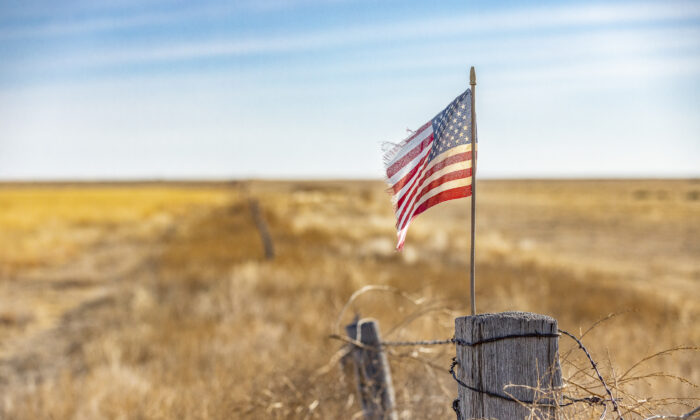 An American flag waves in the window at the edge of a farm outside of Walsh, Colo., on Dec. 6, 2021. (John Fredricks/The Epoch Times)