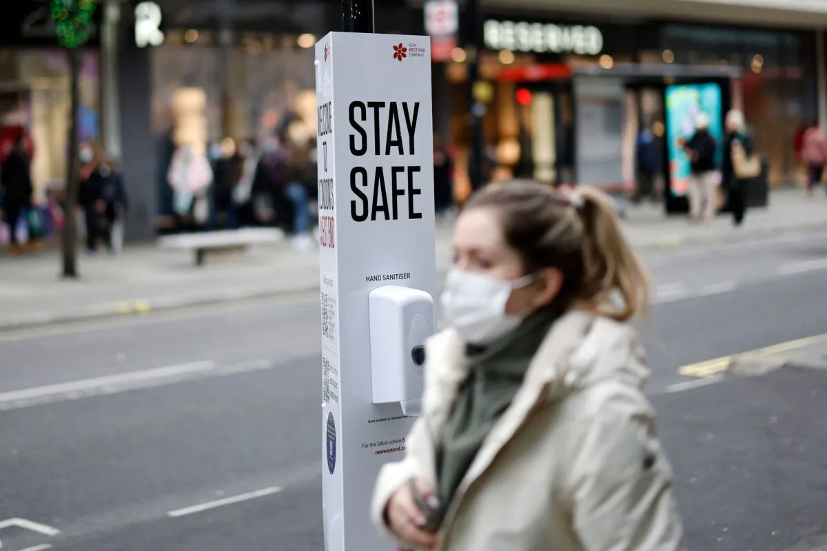A woman walks past a COVID-19 health message sign in London on Dec. 21, 2021. (Tolga Akmen/AFP via Getty Images)