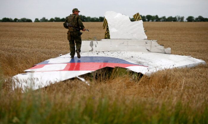 An armed pro-Russian separatist stands on part of the wreckage of the Malaysia Airlines Boeing 777 plane after it crashed near the settlement of Grabovo in the Donetsk region, on July 17, 2014. (Maxim Zmeyev/ Reuters)