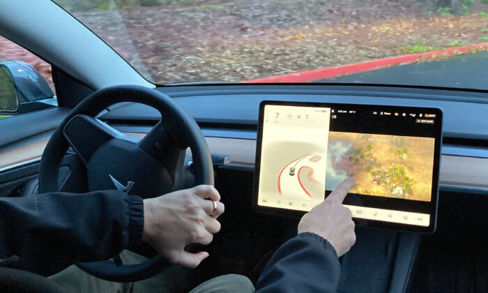 Vince Patton, a new Tesla owner, demonstrates how he can play video games on the vehicle's console while driving, on a closed course in Portland, Ore., on Dec. 8, 2021. (Gillian Flaccus/AP Photo)