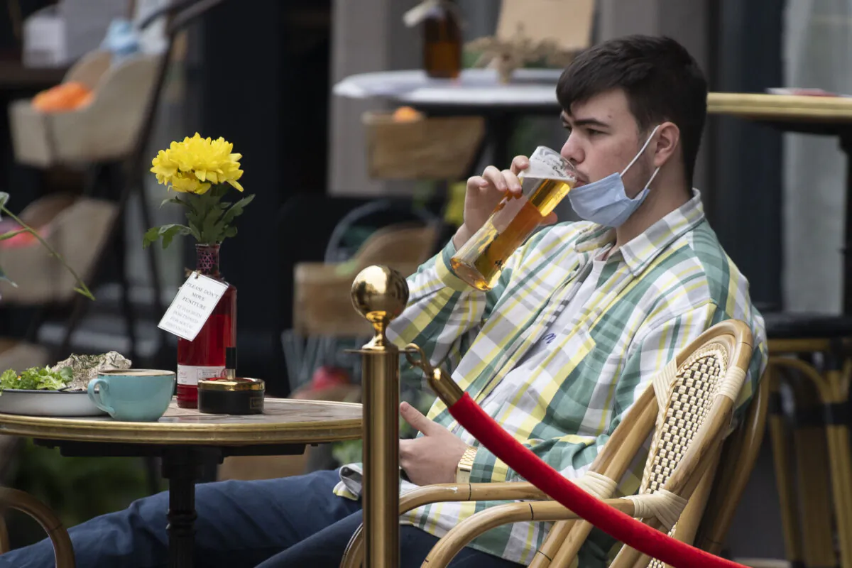 A man drinks a pint with a face mask under his chin on Oct. 19, 2020 in Cardiff, Wales. (Matthew Horwood/Getty Images)