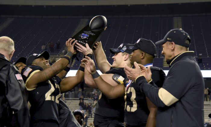 Army head coach Jeff Monken, right, looks on as his team celebrate with the trophy after their win in the Armed Forces Bowl NCAA college football game against Missouri in FORT WORTH, Texas, on Dec. 22, 2021. (Emil Lippe/AP Photo) 