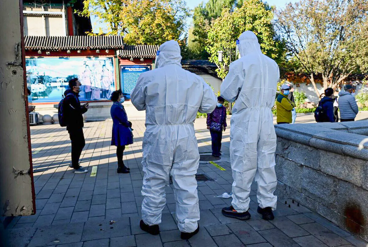 A health workers look at people queueing for swab tests for COVID-19 at a nucleic acid collection station in Beijing on Oct. 26, 2021. (Noel Celis/AFP via Getty Images)